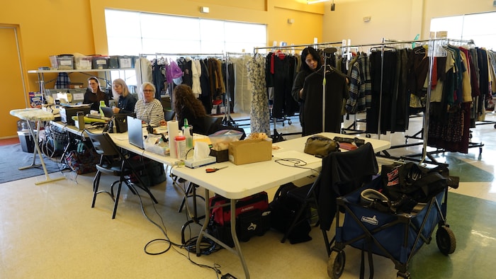 Un costumier aménagé dans une salle avec des femmes assises à des tables.