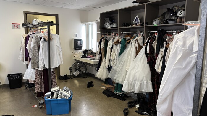 Un costumier avec des robes et autres morceaux de vêtements.