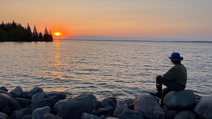 Ue personne observe le coucher de soleil sur le lac, en juillet 2023.