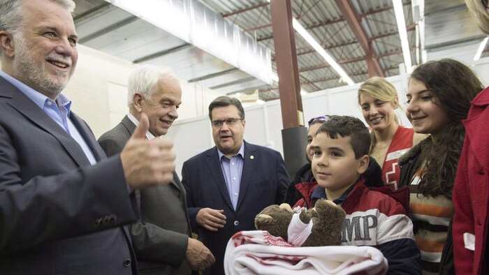 Philippe Couillard, John McCallum, Denis Coderre et Mélanie Joly accueillent des réfugiés syriens à l'aéroport.