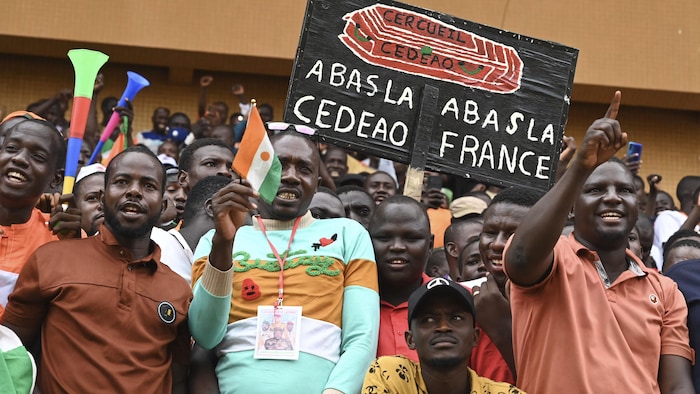 Un homme tient une pancarte «À bas la France, à bas la CEDEAO» lors d'un rassemblement populaire.