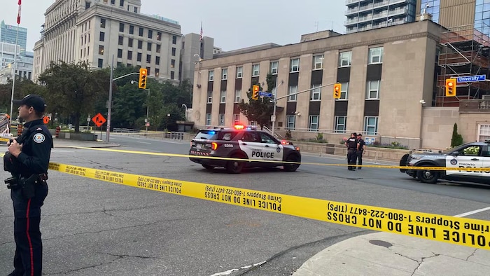 Un policier se tient à l’extérieur du ruban jaune de sécurité devant le consulat des États-Unis.