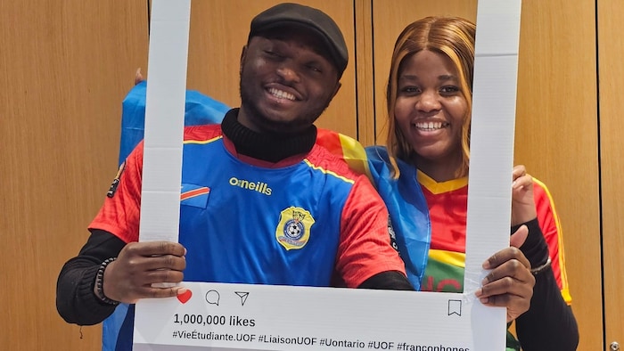 Espoir Masiala, à gauche, porte un maillot de l’équipe nationale de la RDC et sourit à la caméra derrière un décor en carton qui représente une photo Instagram.