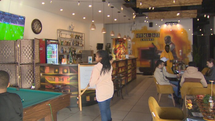 Des personnes dans un restaurant où on voit un écran au mur, le 21 décembre 2025 à Regina.