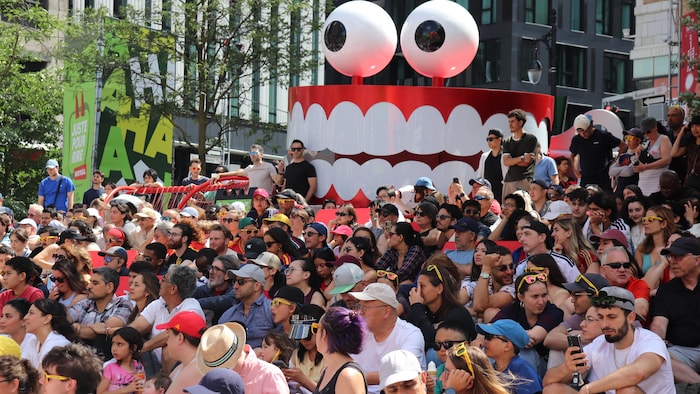 Des partisans attendent le début du match, devant un dentier géant qui sert de décoration au festival Juste pour rire.
