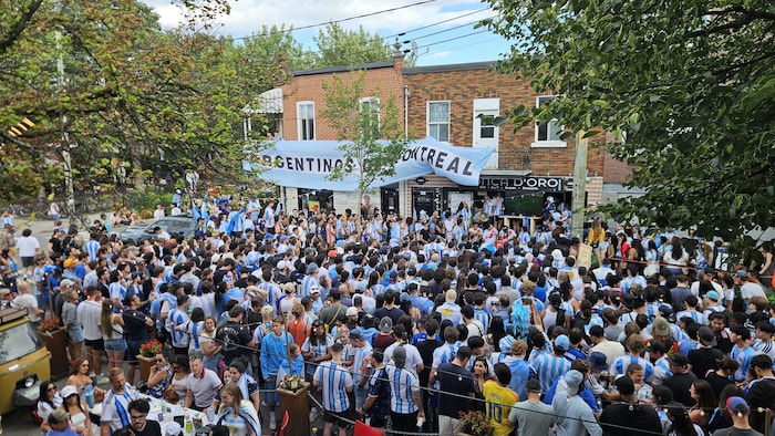 Une foule dans une rue portant des maillots aux couleurs de l'Argentine.