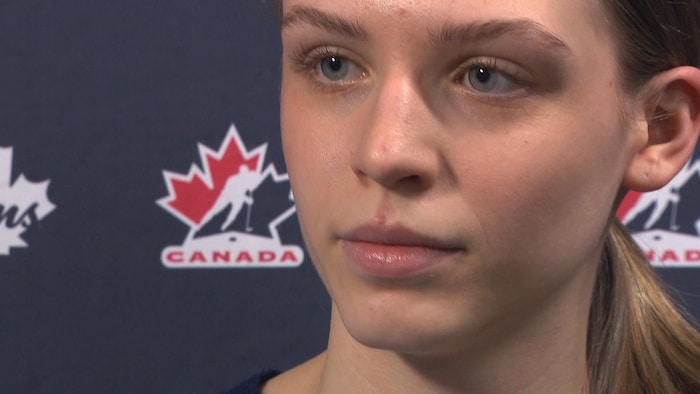 Une adolescente devant un paravent bleu décoré du logo de Hockey Canada.