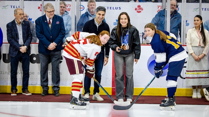 Courtney sarault entre deux joueuses avec rondelle, médailles au cou. 