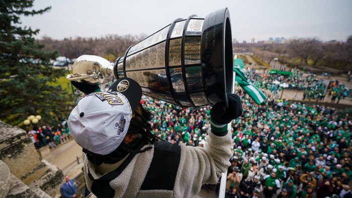 Le receveur des Roughriders, Mario Alford, soulève la coupe Grey sur le balcon du Palais législatif lors du défilé de la Coupe Grey à Regina, en Saskatchewan, le 18 novembre 2025.