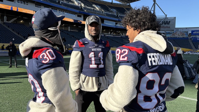 Trois joueurs de football en cercle discutent ensemble.