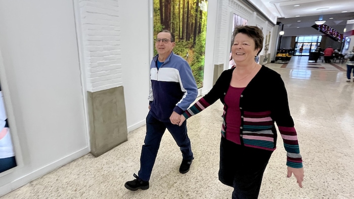 Chantale Ouellet et Richard Jacob marchent main dans la main dans un centre commercial.