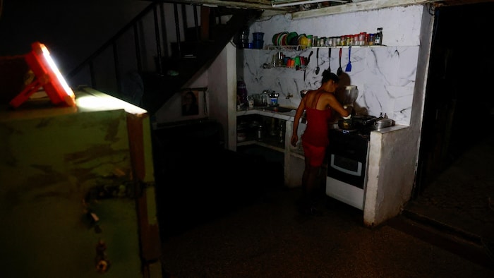 Regla Caridad Gomez, une femme de 46 ans, prépare un repas chez elle dans le noir.