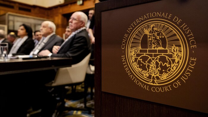 Logo de la Cour internationale de justice avec en arrière-plan des personnes assises devant une table.
