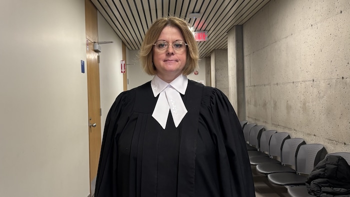 Une avocate en toge pose dans un corridor du palais de justice de Chicoutimi.