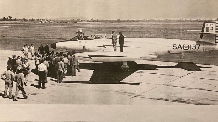Coupure de presse montrant la photo d'un avion bombardier accueilli par de nombreuses personnes sur le tarmac de l'aéroport. 