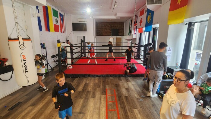 Des enfants s'entrainent dans le ring pendant que d'autres circulent dans la salle d'entrainement.
