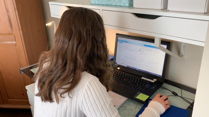 Une élève devant son ordinateur suit un cours en ligne.