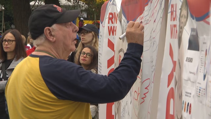 Un homme écrit un message sur une banderole.