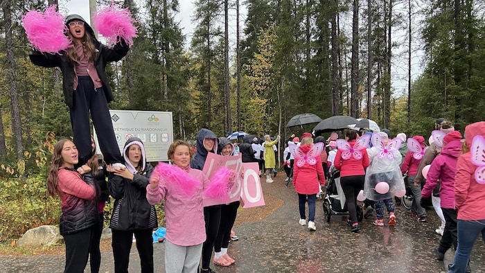 Des gens marchent habillés de rose dans la forêt.