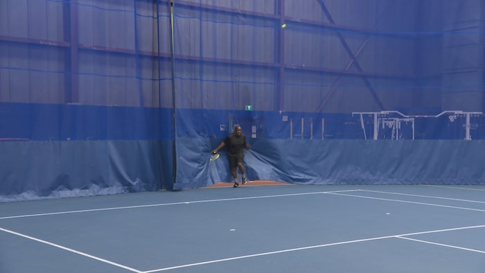 Le journaliste Nouemsi Njiké est en difficulté alors qu'il tente de renvoyer une balle de tennis.