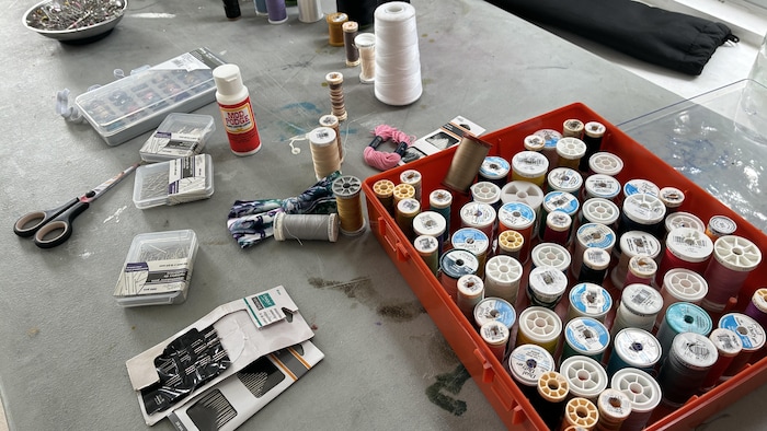 Des rouleaux de fils et des aiguilles de couture sur une table.