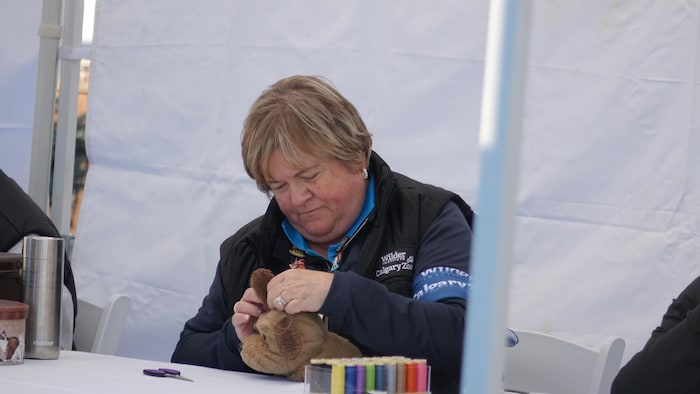 Une couturière recout l'oreille d'un chien en peluche.