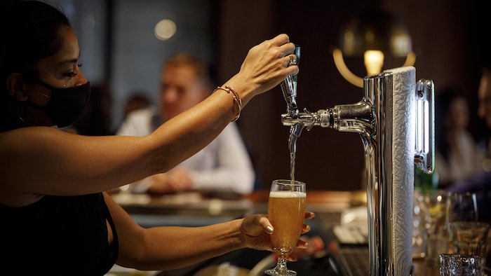 Une serveuse verse une bière dans un verre dans un bar.