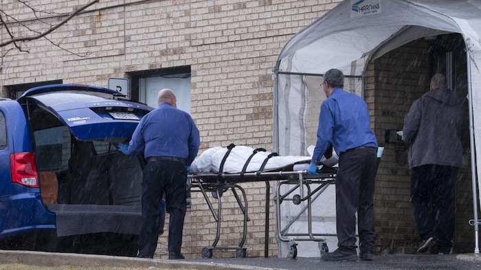 Deux employés d’un centre funéraire évacuant un cadavre du centre.
