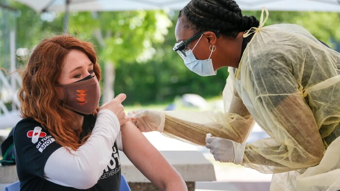 Olympic medalist Clara Hughes, left, receives a second dose of COVID-19 vaccine at a community vaccination clinic at the Stoney Nakoda First Nation health services centre in Morley, Alta., on Thursday.