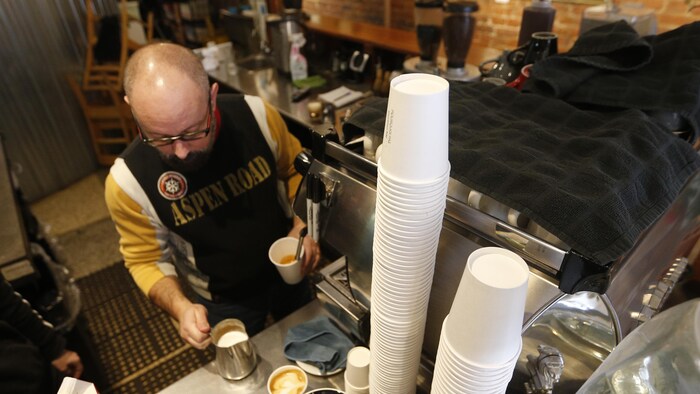 Un employé dans le commerce Le Pourquoi pas espresso-bar prépare un café.