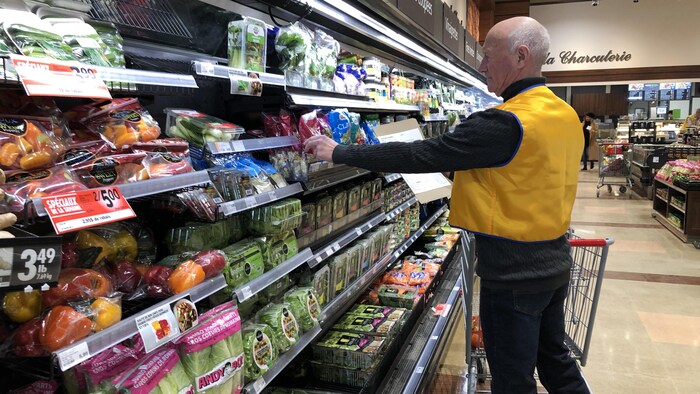 Un homme devant un étalage d'épicerie.