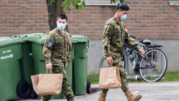 Members of the Canadian Armed Forces walking outside a brick building.