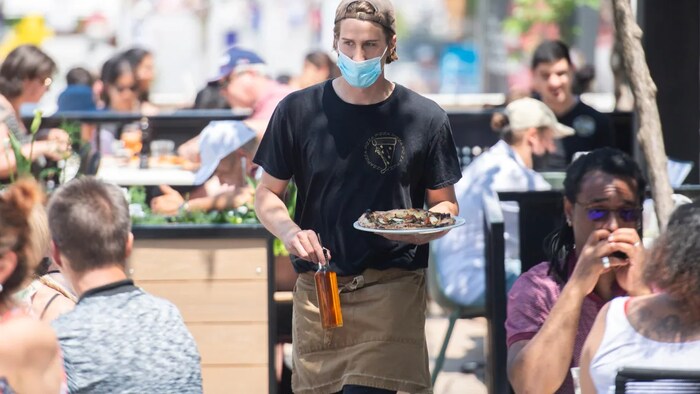 A server brings an order to a customer at a restaurant in Montreal on June 6, as the COVID-19 pandemic continues in Canada and around the world.