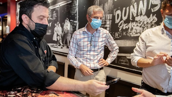 Jimmy Staveris, manager of Dunn's Famous restaurant scans the COVID-19 QR codes of customers in Montreal earlier this month as the Quebec government's COVID-19 vaccine passport came into effect.