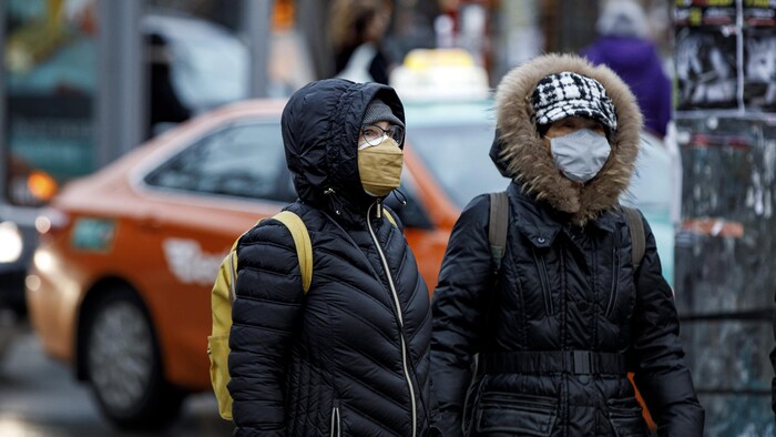 Des passants dans la rue à Toronto portant un masque.