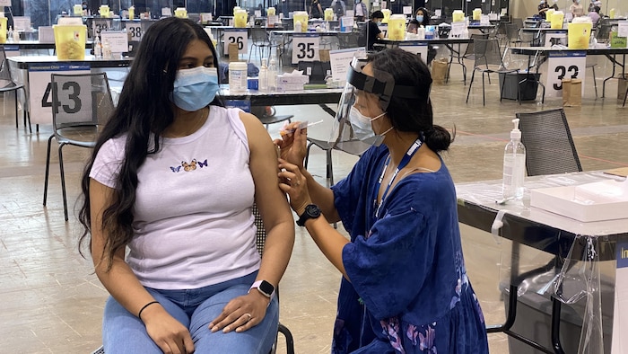 Une Torontoise se fait injecter le vaccin dans l'épaule dans un centre d'immunisation de masse.