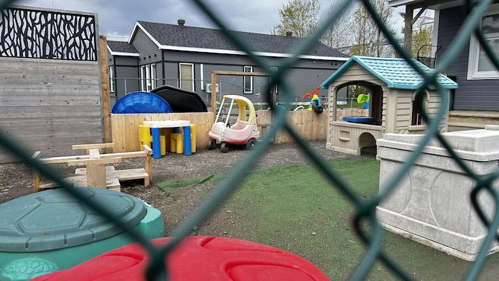 Une cour clôturée contenant de nombreux jeux pour les bambins.