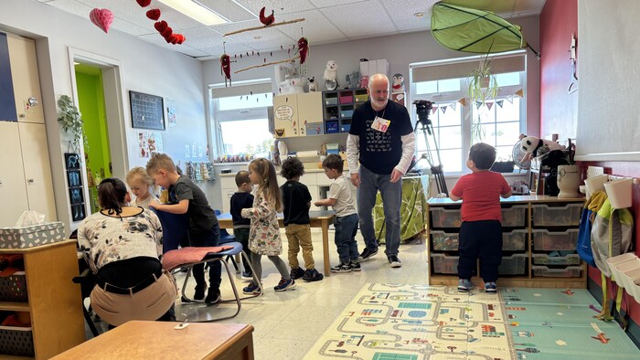 Des enfants jouent dans un CPE sous le regard de leur éducateur.
