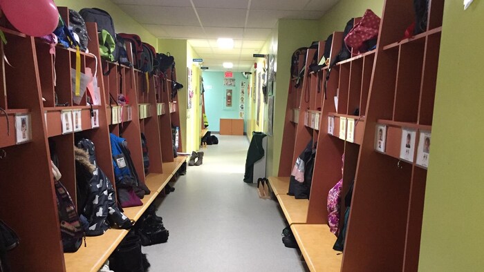 Des bancs et des casiers sont aménagés dans un couloir pour accueillir les vêtements et les sacs à dos dans un CPE.