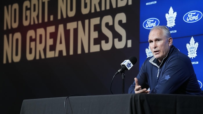 Craig Berube parle au micro devant une enseigne de l’équipe.