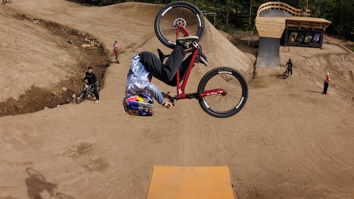 Au sommet d'un saut, un cycliste fait une figure dans les airs.