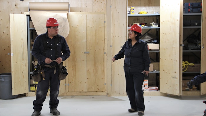 Deux personnes en tenue de travail discutent.