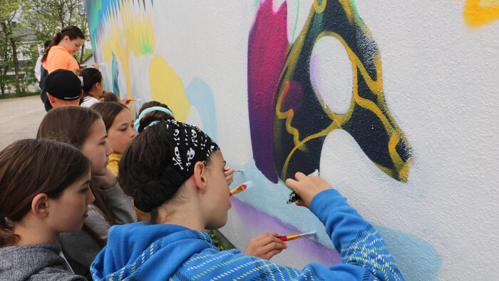 Des jeunes en train de peindre une murale.