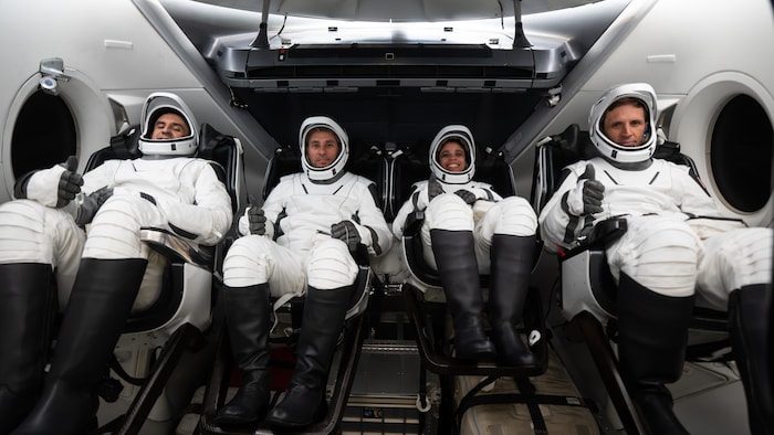 Quatre personnes sont assises dans une installation de simulation de mission spatiale.