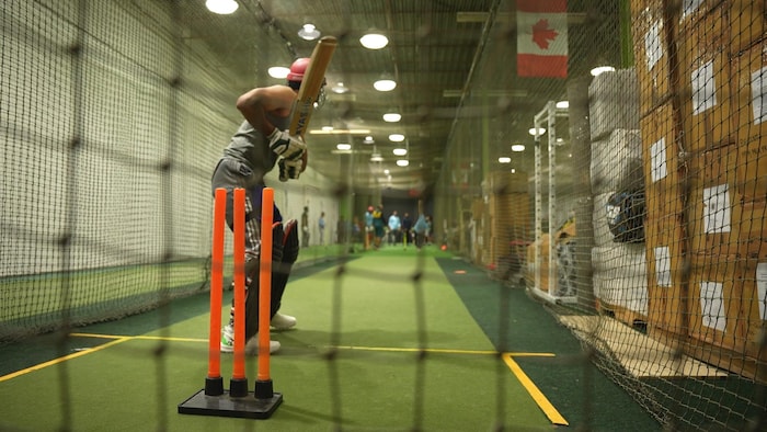 Un joueur de cricket s'apprête à s'élancer dans une cage de frappeur.