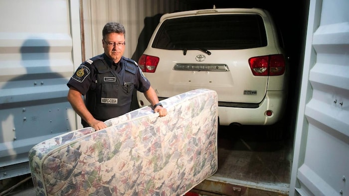 A man removes a mattress used to conceal a stolen vehicle in a container.