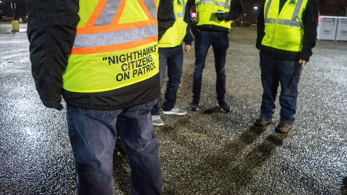 Des hommes portant des dossards jaunes avec la mention Nighthawks Citizens on Patrol.