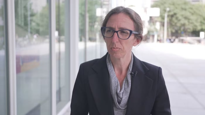 Alison Craig en lunettes et veste noire.