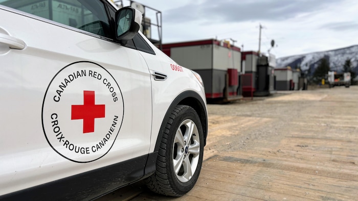 Une camionnette de la Croix-Rouge avec des maisons mobiles en arrière-plan.