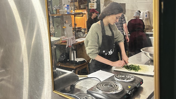 Une jeune femme hache du persil sur une planche à découper. 